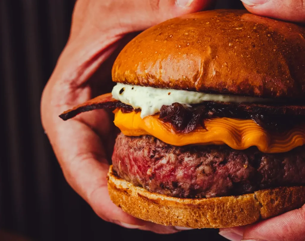 hand holding burger with grilled handcrafted barbeque pork patty Abrahams Sausages  Meats Malaysia